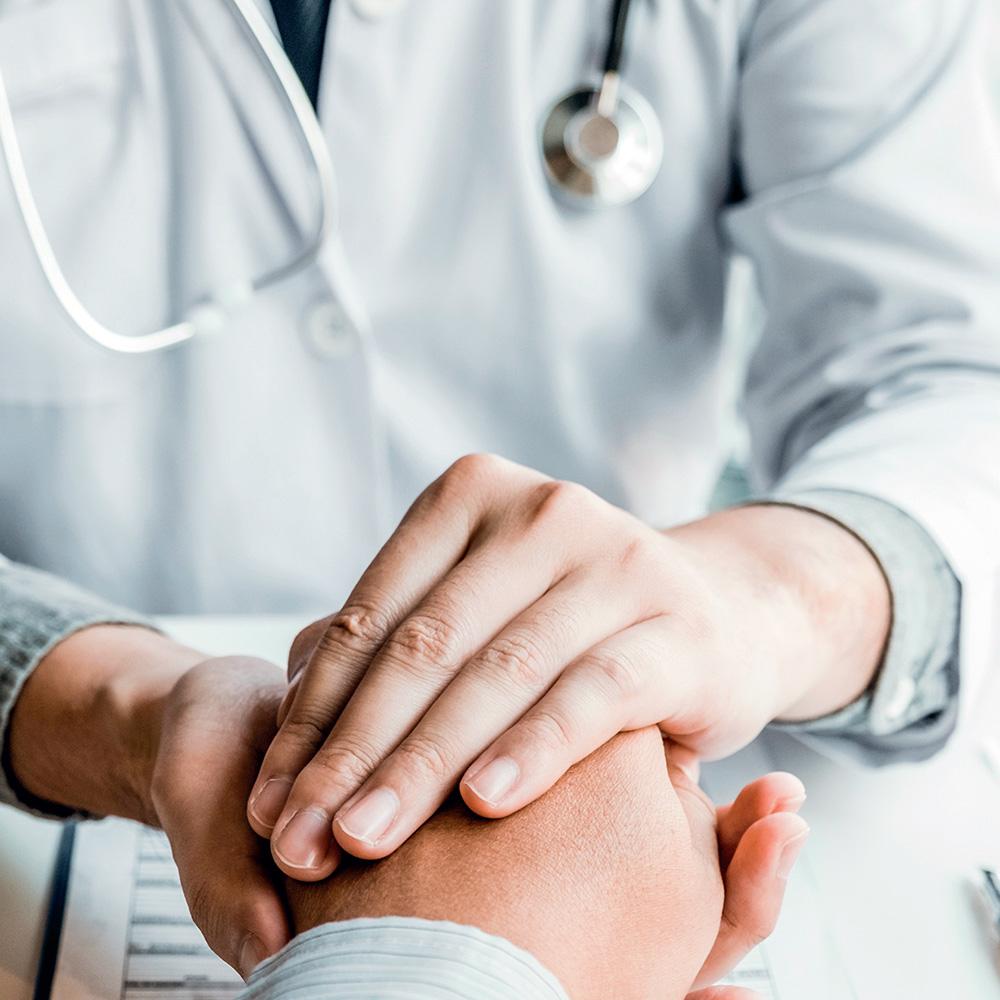 A doctor holding a patient's hand in both hands